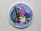 First view of Pinkish purple gnome in a purple circle with a wagon wheel and a vase of lavender flowers minder.