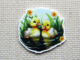 First view of A pair of ducklings learning how to swim with yellow flowers minder.