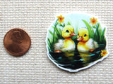 Second view of A pair of ducklings learning how to swim with yellow flowers minder.