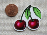 Second  view of a pair of cherries on stems with green leaves minder.