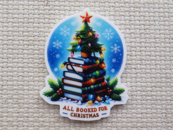 Small Christmas tree sitting on top of a stack of colorful books with a string of lights in front of a winter night circle with the words 