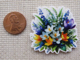 White, yellow and blue flowers in a beautiful arrangement minder with penny for scale.
