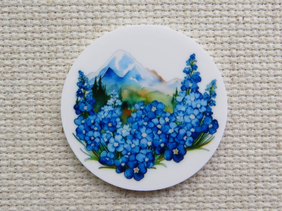 First  view of circle minder with blue flowers along the front and a mountain in the background.