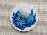 First  view of circle minder with blue flowers along the front and a mountain in the background.