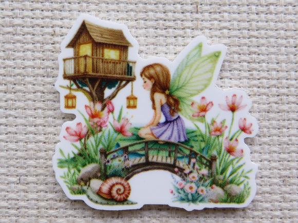 Minder of a fairy sitting on a bridge with flowers and a treehouse in the background