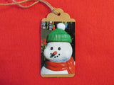 Snowman with green hat and red scarf gift tag.