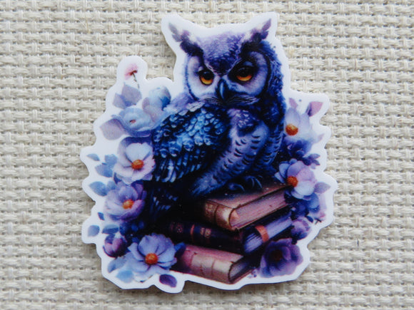Minder of an owl sitting on books with floral elements.