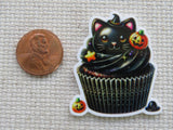 Halloween-themed cupcake minder with a black cat design next to a penny for scale.