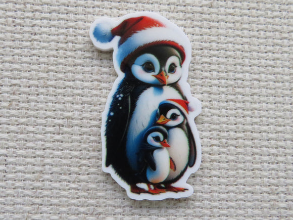 A trio of penguins where two of them are wearing Santa hats minder.