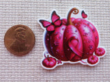 Decorative pink pumpkin minder with a butterfly next to a penny 