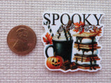 Minder with 'Spooky Season' text, pumpkin, and other Halloween elements next to a penny for scale.