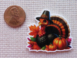 Minder of a turkey with pumpkins and leaves next to a penny.