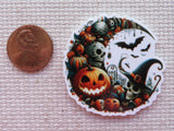 Halloween-themed minder with pumpkins, skulls, and bats next to a penny for scale.