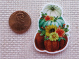 Decorative minder of pumpkins with flowers next to a penny on a textured surface