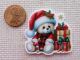 Christmas-themed minder of a bear with presents and a penny for scale on a textured surface.