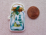 Minder of a snowy scene in a jar next to a penny on a textured surface