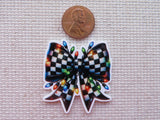 Colorful checkered bow with Christmas lights minder next to a penny on a textured surface