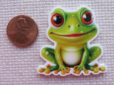Cartoon frog minder next to a penny on a textured surface