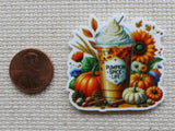 Minder of a pumpkin spice latte with pumpkins and flowers next to a penny for scale.