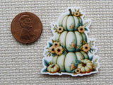 Minder of pumpkins and flowers next to a penny.