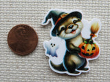 Halloween-themed minder of an otter in a witch hat with a pumpkin, next to a penny for scale.