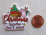 Christmas-themed minder with 'Calories Don't Count' text next to a penny for size comparison on a textured background.