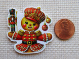 Decorative minder of a nutcracker character next to a penny for scale on a textured surface.