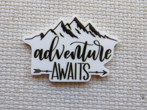 Mountain-shaped minder with 'adventure awaits' text on a textured beige background