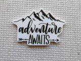 Mountain-shaped minder with 'adventure awaits' text on a textured beige background