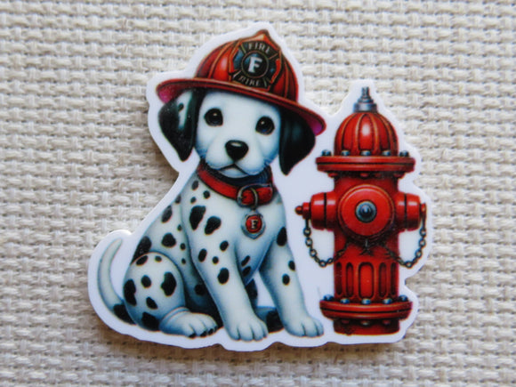 This adorable dalmatian puppy minder is wearing a fireman's helmet, has a red collar on and is sitting next to a red fire hydrant.