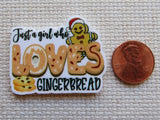 Minder with gingerbread-themed text and graphics next to a penny for size comparison on a textured surface.