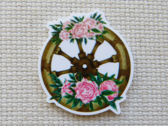 First view of a wooden wagon wheel minder with pink flowers.