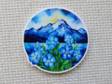 Round minder with blue floral and mountain design on a textured surface