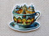 Decorative minder of a teacup with a Christmas village scene on a textured beige background