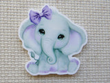 Minder of a cute elephant with a purple bow on a textured beige background