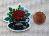 Minder with a red rose and coffee cup design, next to a penny for scale.