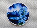 Minder with blue floral design and mountain landscape on a textured beige background