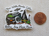 Halloween-themed minder with coffee cup and witch elements next to a penny for scale.