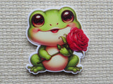 Cartoon frog holding a red rose minder on a textured beige background