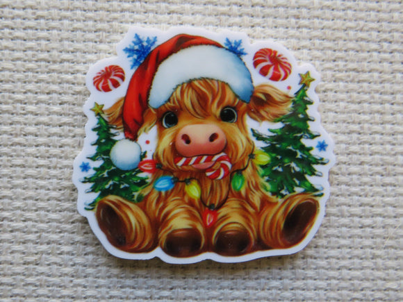 Minder of a cow wearing a Santa hat with Christmas decorations on a textured surface