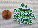 Minder with 'Happy St. Patrick's Day' text and clover leaves next to a penny on a textured surface.