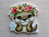 Minder of an otter with a floral headband on a textured surface