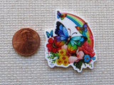 Colorful butterfly and rainbow minder next to a penny on a textured surface