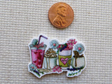 Minder of drinks with flowers and a penny for scale on a textured surface