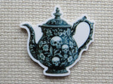 Teapot-shaped decorative minder with skull and floral design on a textured surface