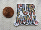 Minder with 'FUR MAMA' text and paw prints next to a penny on a textured surface