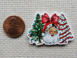 Christmas-themed minder with Santa Claus, tree, and treat tree next to a penny for scale on a textured surface.