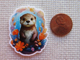 Minder of an otter surrounded by flowers next to a penny for scale on a textured surface