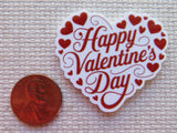 Heart-shaped 'Happy Valentine's Day' minder with red hearts and text, next to a penny for size comparison on a textured surface.