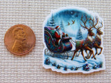Minder of Santa Claus in a sleigh pulled by reindeer next to a penny on a textured surface